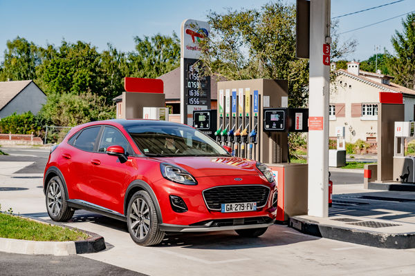 voiture Ford rouge à une station essence